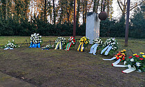Kränze vor der symbolischen Glocke des Denkmals auf dem Westfriedhof