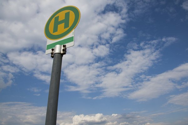 Ein Haltestellenschild vor leicht bewölktem Himmel