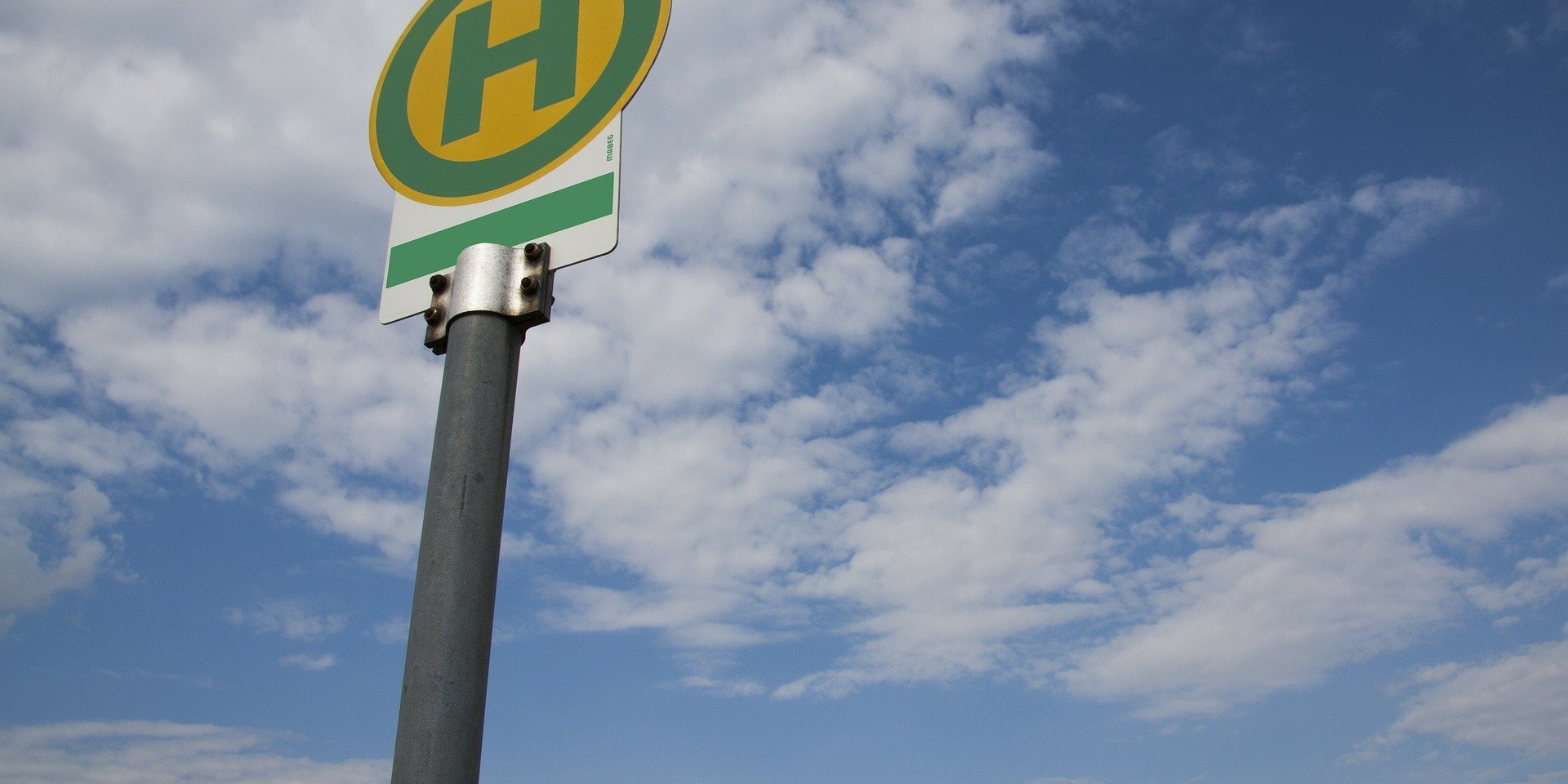 Ein Haltestellenschild vor leicht bewölktem Himmel