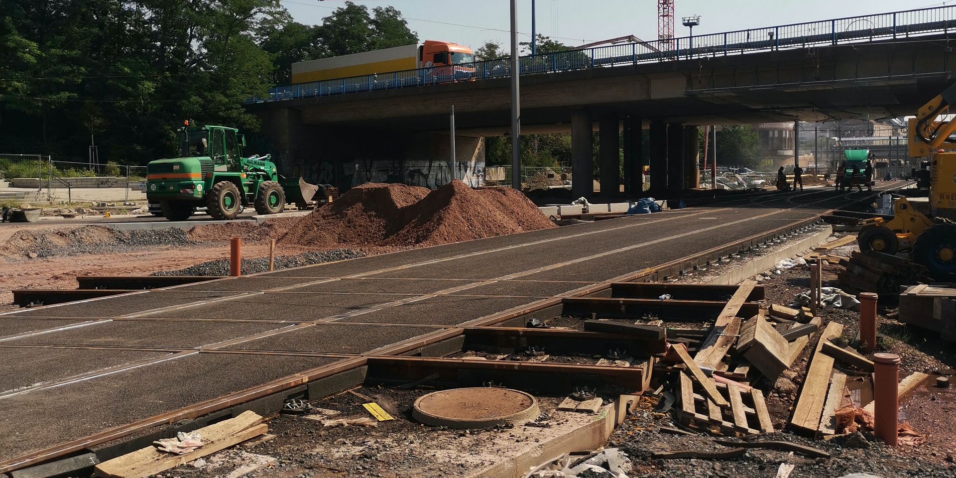 Farbbild einer Baustelle, im Hinrtergrund eine Brücke