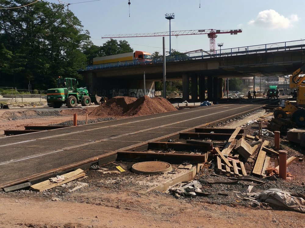 Farbbild einer Baustelle, im Hinrtergrund eine Brücke