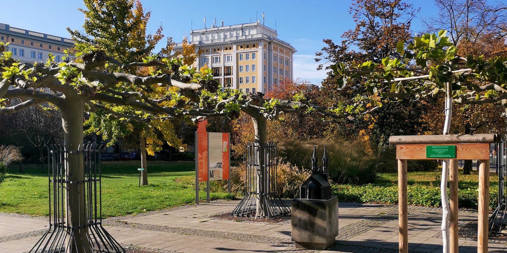 Blick auf eine kleine Parkanlage mit einem bronzedenkmal für eine Kirche